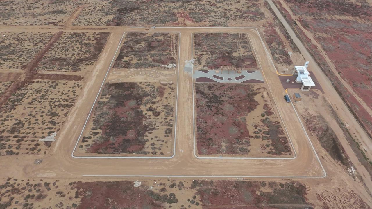 Vista aérea real: calles blancas, cordón de banqueta y área verde con pérgola
