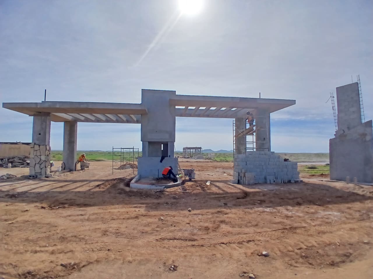 Caseta de acceso en construcción: estructura de concreto, andamios y muros de block